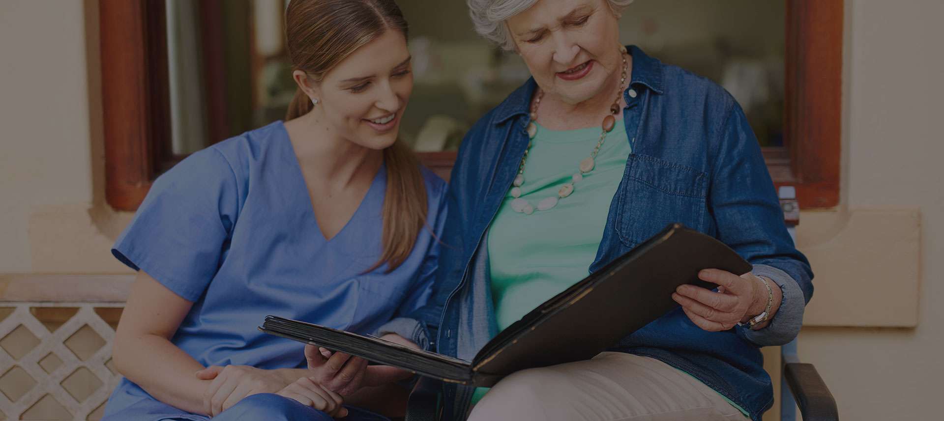 Caregiver and senior looking at photo album.