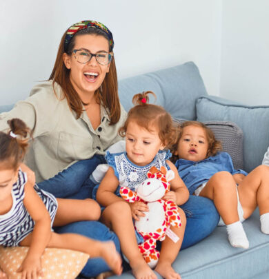 A woman sitting on top of a couch next to several children.
