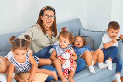 A woman sitting on top of a couch next to several children.