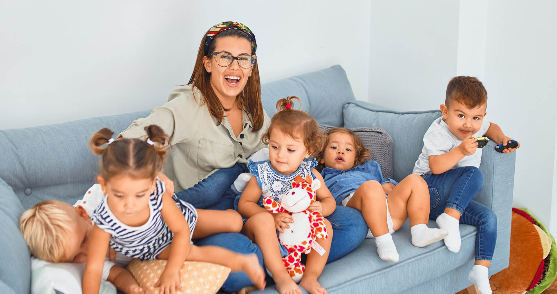 A woman sitting on top of a couch next to several children.