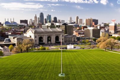 A view of the city from above shows a grassy field and buildings.