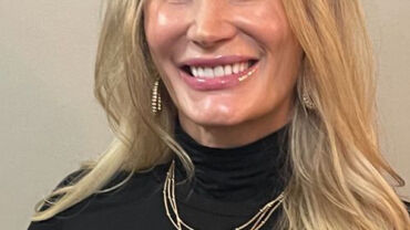 A woman with long blonde hair wearing black.