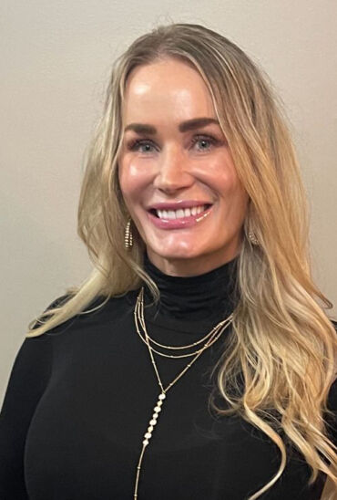 A woman with long blonde hair wearing black.