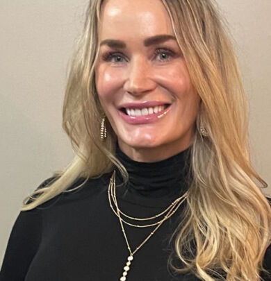 A woman with long blonde hair wearing black.