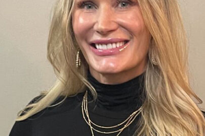 A woman with long blonde hair wearing black.