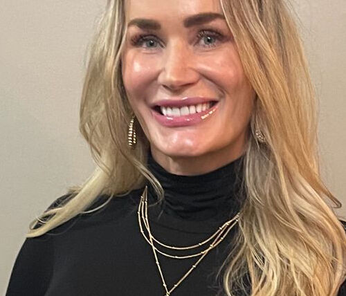 A woman with long blonde hair wearing black.