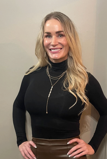 A woman in black shirt and necklace smiling for the camera.