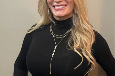 A woman in black shirt and necklace smiling for the camera.